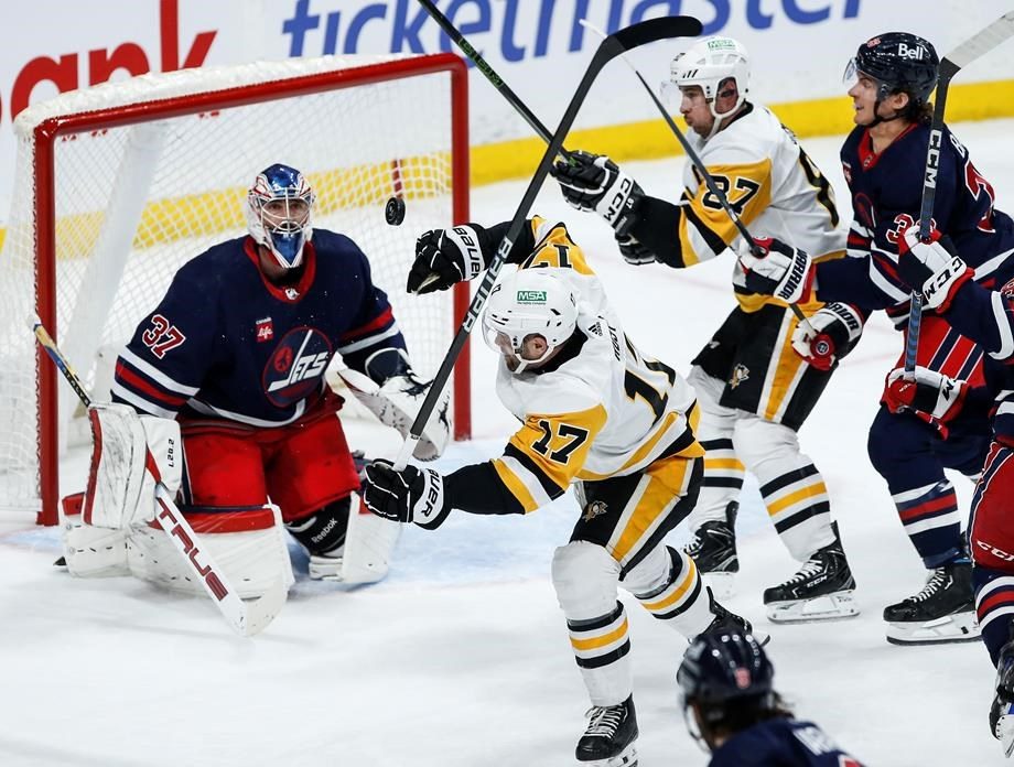 Winnipeg Jets goaltender Connor Hellebuyck (37) keeps his eye on the loose puck as Pittsburgh Penguins' Bryan Rust (17) and Sidney Crosby (87) battle Jets' Morgan Barron (36) during second-period NHL action in Winnipeg on Saturday, Feb. 10, 2024.