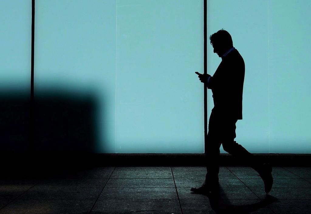 FILE - A man walks and texts on his smart phone in downtown Toronto, Monday, Oct. 30, 2017. THE CANADIAN PRESS/Nathan Denette.