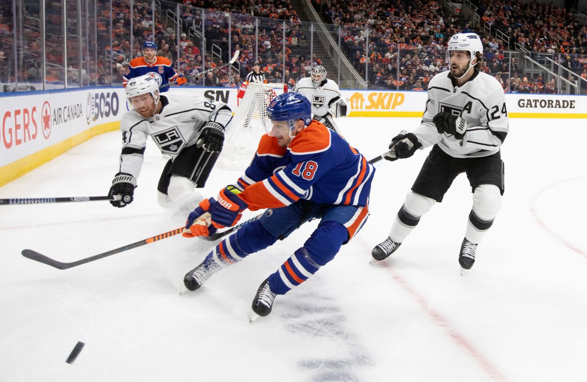 Los Angles Kings' Vladislav Gavrikov (84) and Phillip Danault (24) battle for the puck with Edmonton Oilers' Zach Hyman (18) during second period NHL action in Edmonton on Monday February 26, 2024.