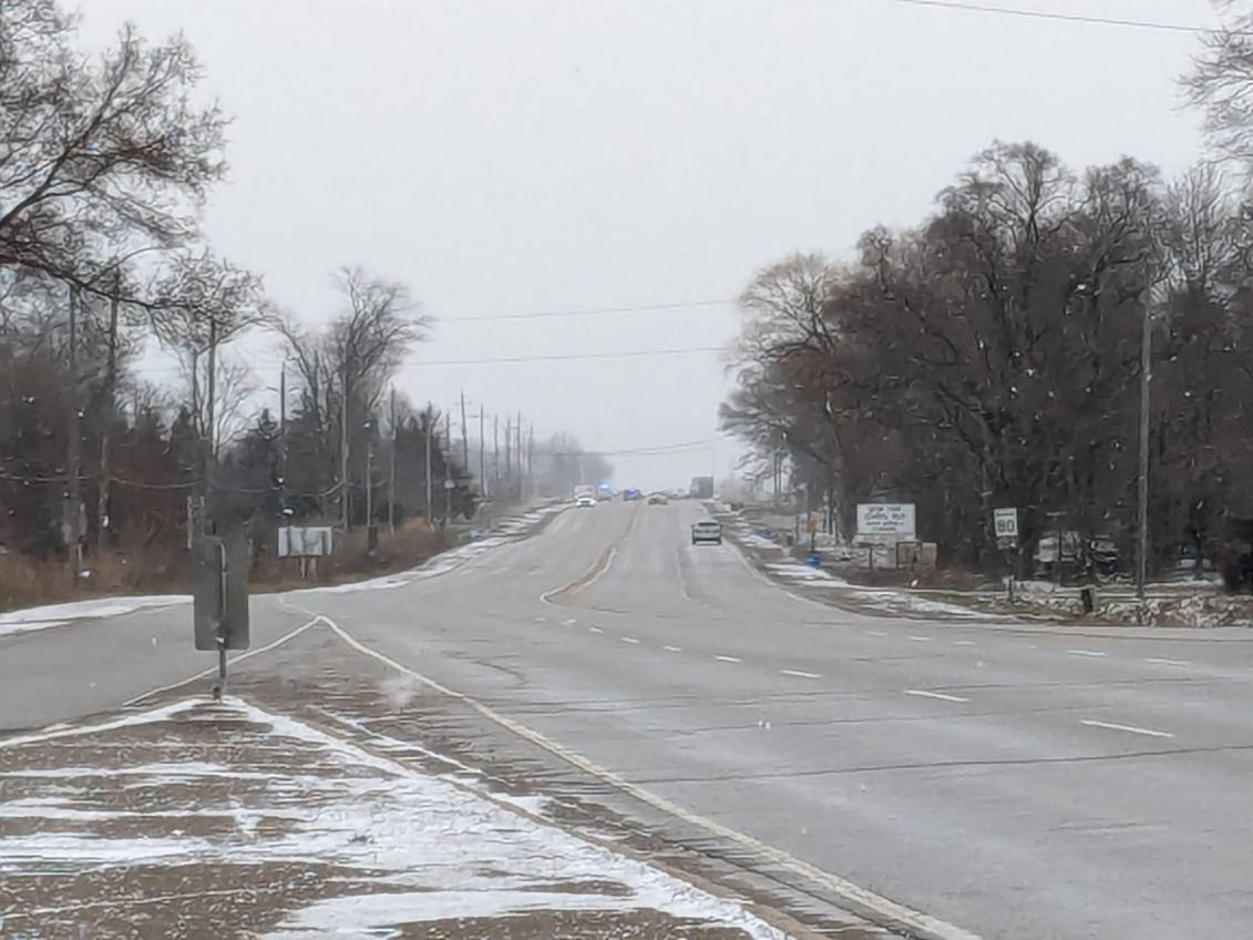Emergency vehicles seen in the distance from a snowy road.