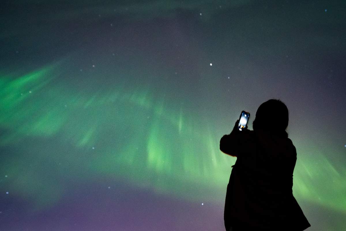 A person takes a photo of aurora borealis (northern lights) in Vancouver, B.C., Saturday, May. 11, 2024. Space Weather Canada warned the public that a “major geomagnetic storm” alert was in effect Friday, which might cause “ionospheric disturbances,” and was expected to continue into early Saturday as a series of strong solar particle releases reach the Earth. THE CANADIAN PRESS/Ethan Cairns