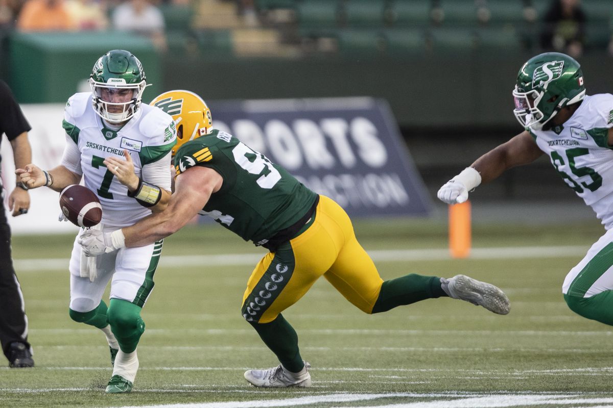 Saskatchewan Roughriders quarterback Cody Fajardo (7) fumbles the ball under pressure from Edmonton Elks defensive lineman Jake Ceresna (94) during first half CFL action in Edmonton, Alta., on Saturday August 13, 2022.