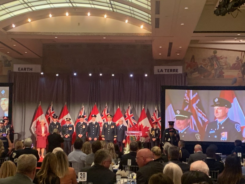A group of firefighters in front of flags at an award ceremony.