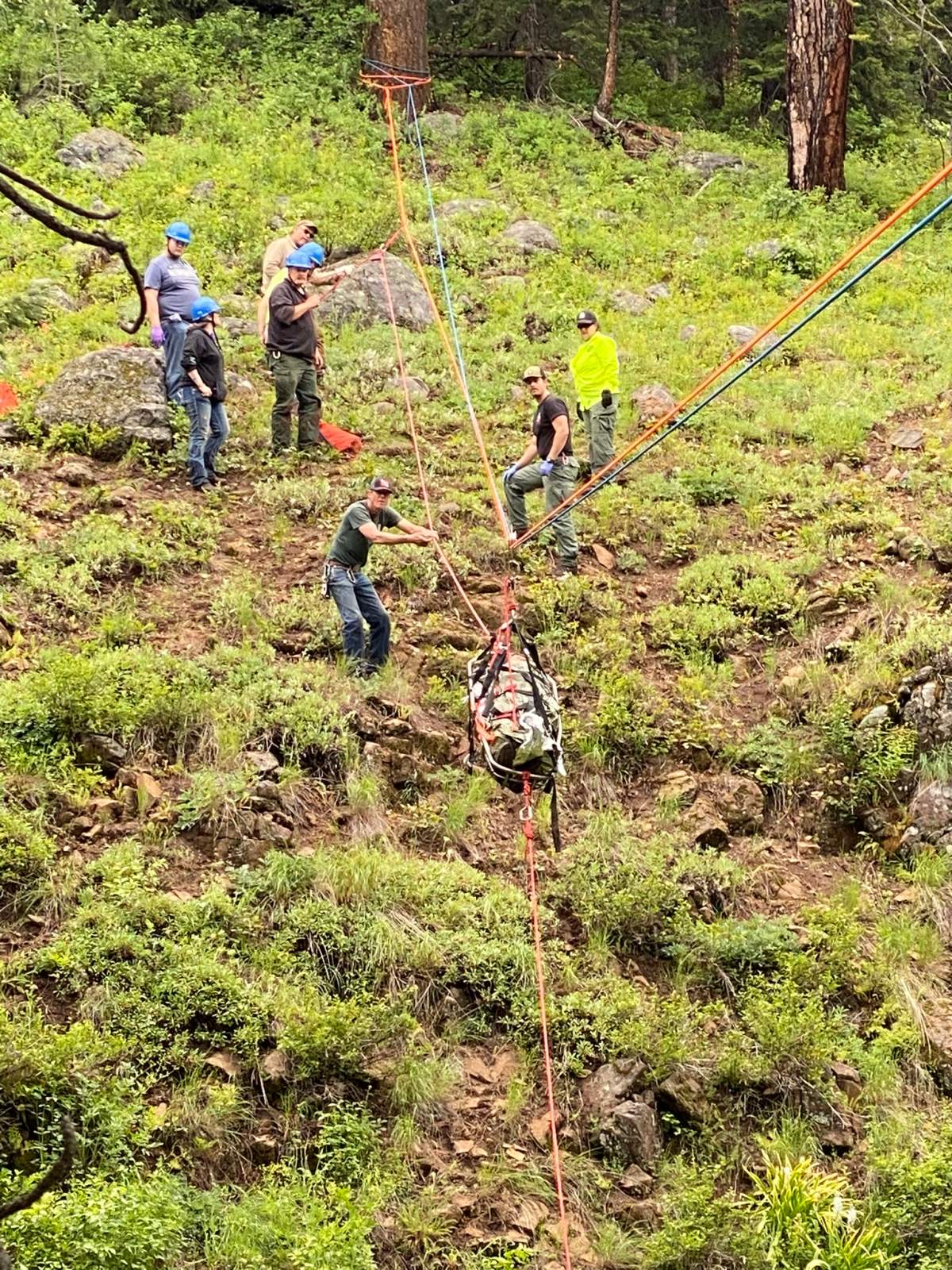 A man is wrapped up and being transported using a rope system.