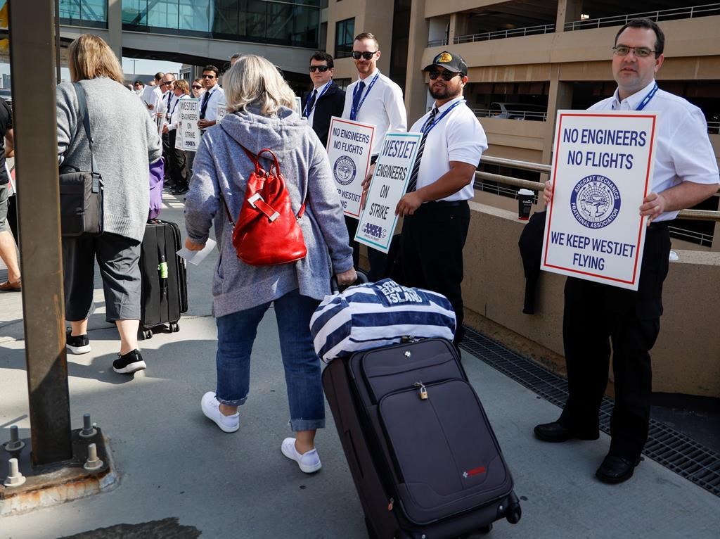 WestJet says there will still be flight disruptions, including cancellations, this week after a deal was reached to end a strike by its mechanics. Passengers make their way past striking WestJet mechanics at Calgary International Airport in Calgary, Saturday, June 29, 2024.