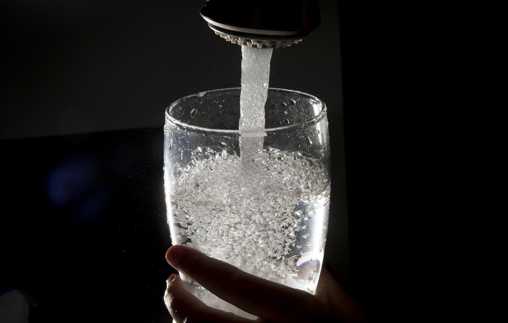 Drinking water is poured into a glass from a faucet.