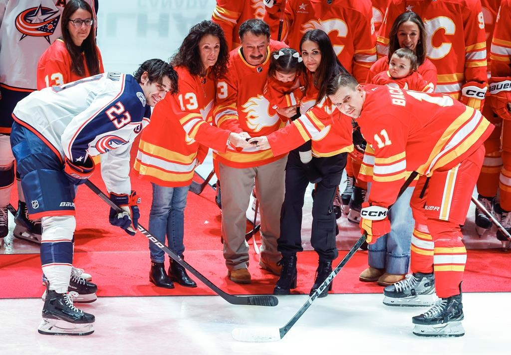 Columbus Blue Jackets' Sean Monahan, left, and Calgary Flames' Mikael Backlund join the family of Johnny Gaudreau at centre ice before first period NHL hockey action in Calgary on Tuesday, Dec. 3, 2024.