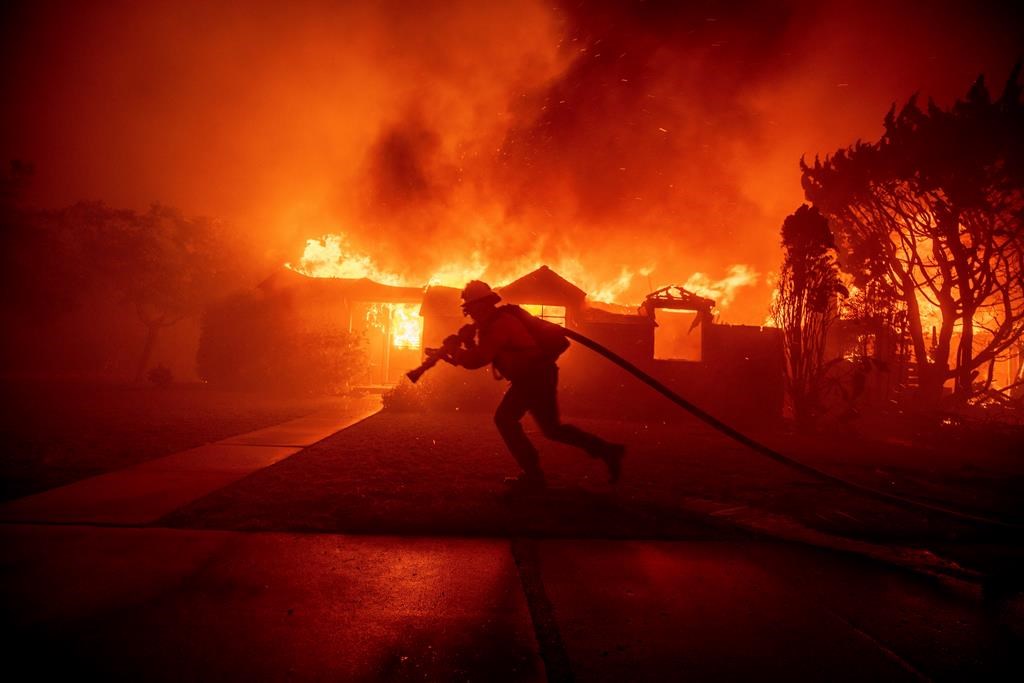 A firefighter battles the Palisades Fire as it burns a structure in the Pacific Palisades neighbourhood of Los Angeles, Tuesday, Jan. 7, 2025.