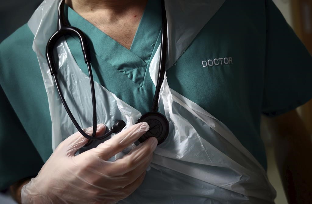 A junior doctor holds his stethoscope during a patient visit on Ward C22 at the Royal Blackburn Teaching Hospital, in Blackburn, England, Thursday, May 14, 2020.