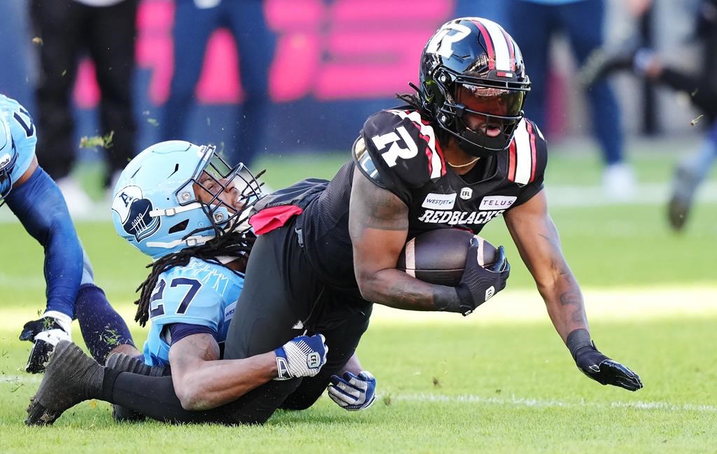 Ottawa Redblacks wide receiver Bralon Addison (right) is tackled by Toronto Argonauts defensive back Mark Milton (27) during Eastern Conference semifinal CFL football action in Toronto on Saturday, November 2, 2024. The Redblacks signed veteran American receiver Addison to a one-year contract extension Wednesday.THE CANADIAN PRESS/Nathan Denette.