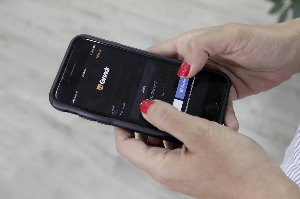 In this Wednesday, May 29, 2019, file photo, a woman looks at the Grindr app on her mobile phone.
