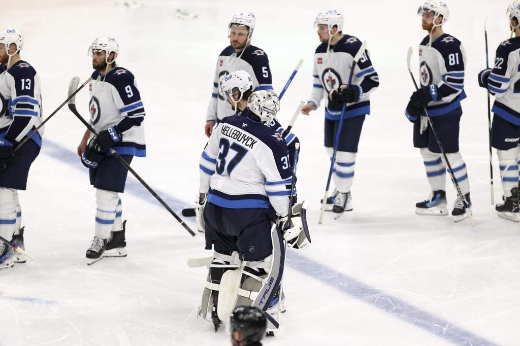 Winnipeg Jets' Connor Hellebuyck (37) and Mark Scheifele (55) join the hand shake line after their loss in overtime to the Dallas Stars in Game 6 of a second-round NHL hockey playoff series in Dallas, Saturday, May 17, 2025. (AP Photo/Gareth Patterson).