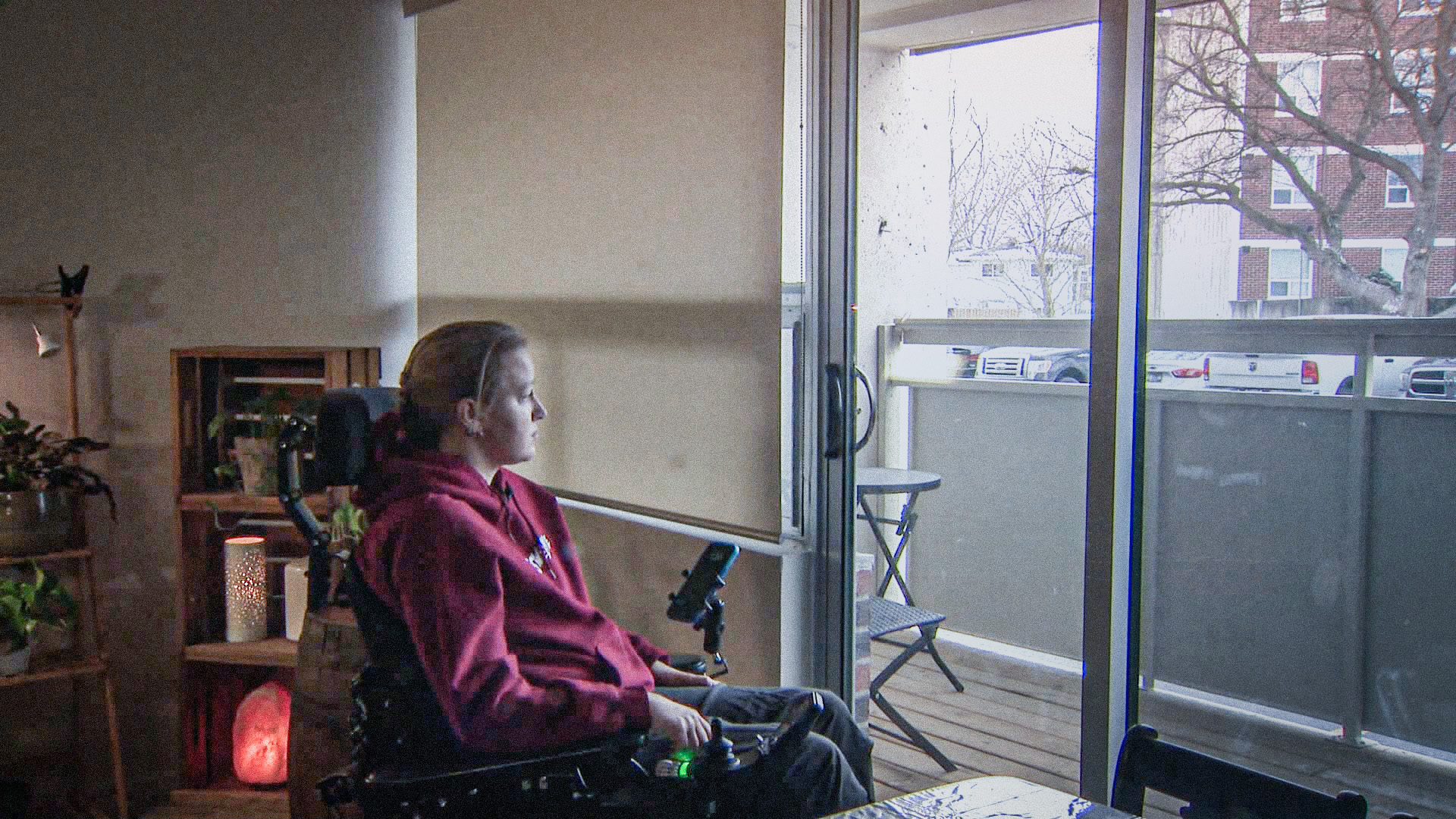 Photo of Kayla Pollock sitting in wheelchair and looking out window