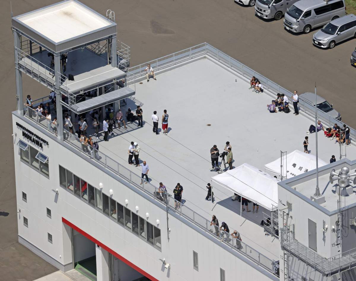 July 30, 2025: Photo taken from a Kyodo News helicopter shows people who evacuated to the rooftop of a fire department building in Mukawa, Hokkaido, northern Japan, on July 30, 2025, after the Japan Meteorological Agency issued a tsunami warning for the country’s Pacific coast following a powerful earthquake off Russia’s Kamchatka Peninsula. (Kyodo).==Kyodo.