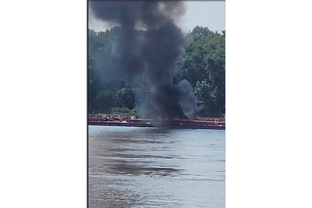 This image provided by Adam Briggs shows smoke fills the air from a barge after a helicopter crash in the Mississippi River near Alton, Ill., on Thursday, Aug. 7, 2025.