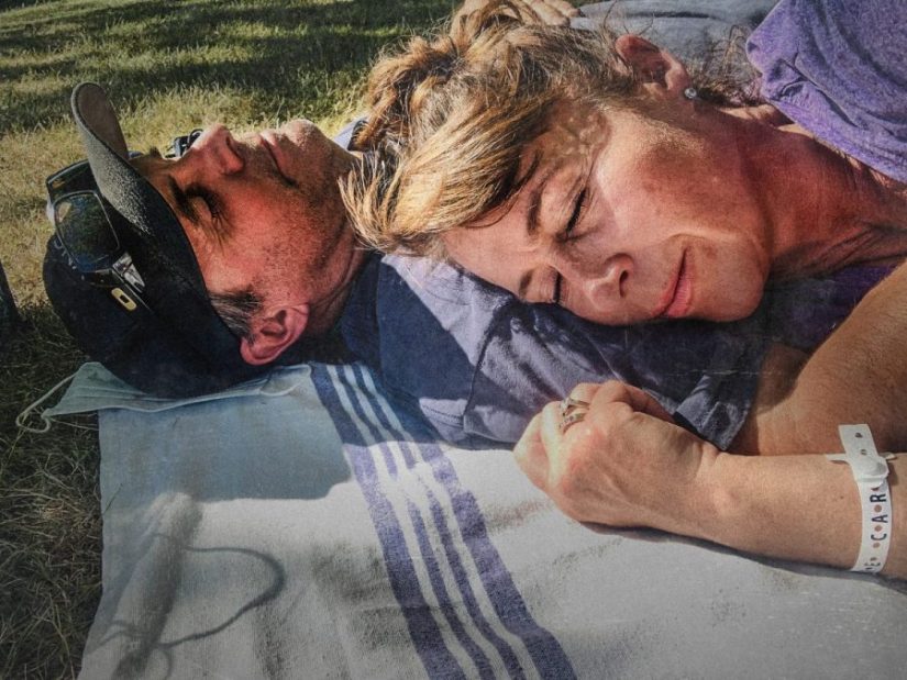 Carol Messenger and her husband eyes closed and lying on blanket on lawn of hospital in 2021