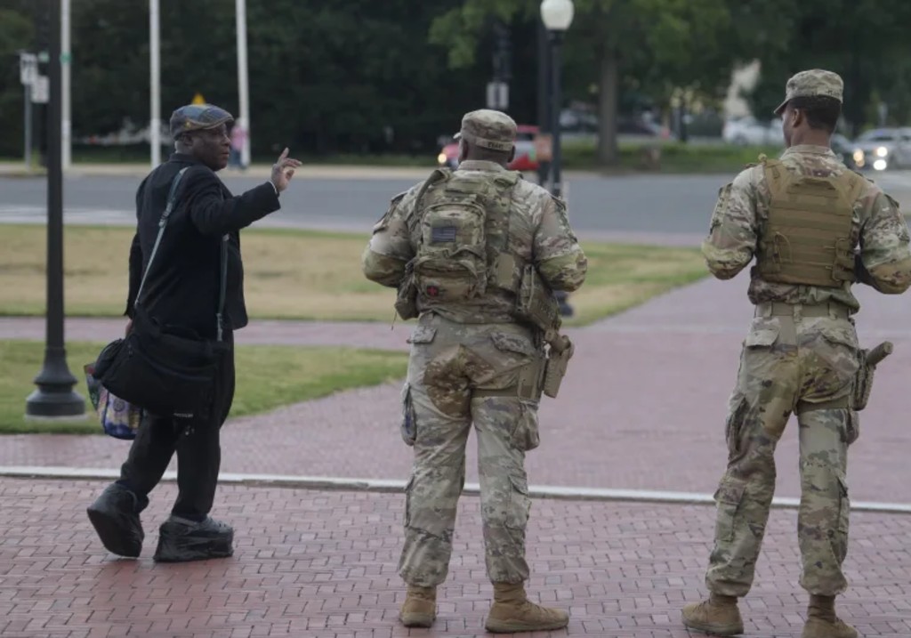 Armed members of the South Carolina National Guard talk with a man while positioned outside of Union Station in Washington, Sunday, Aug. 24, 2025.