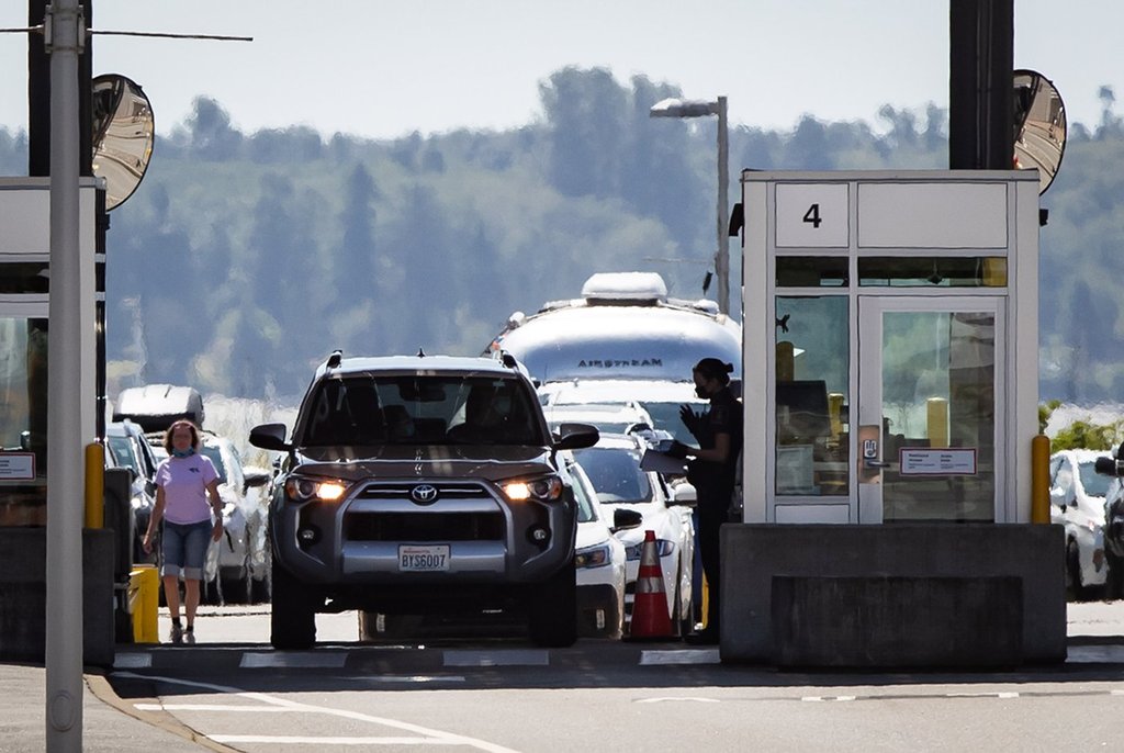 A Canada Border Services Agency officer speaks to a motorist entering Canada at the Douglas-Peace Arch border crossing, in Surrey, B.C., on Monday, August 9, 2021. THE CANADIAN PRESS/Darryl Dyck.
