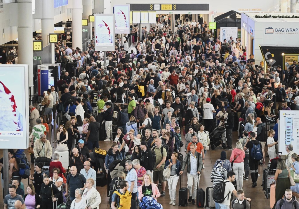 People walk by a departures board after a cyber attack caused delays at Brussels International Airport in Zaventem, Belgium, Saturday, Sept. 20, 2025.