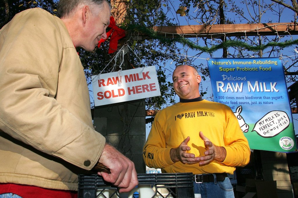 FILE - Veterinarian Patrick Smith, left, discusses raw milk with dairyman and producer Mark McAfee at the Farmer's Market in Fresno, Calif., on Saturday, Dec. 22, 2007. (AP Photo/Gary Kazanjian, File).