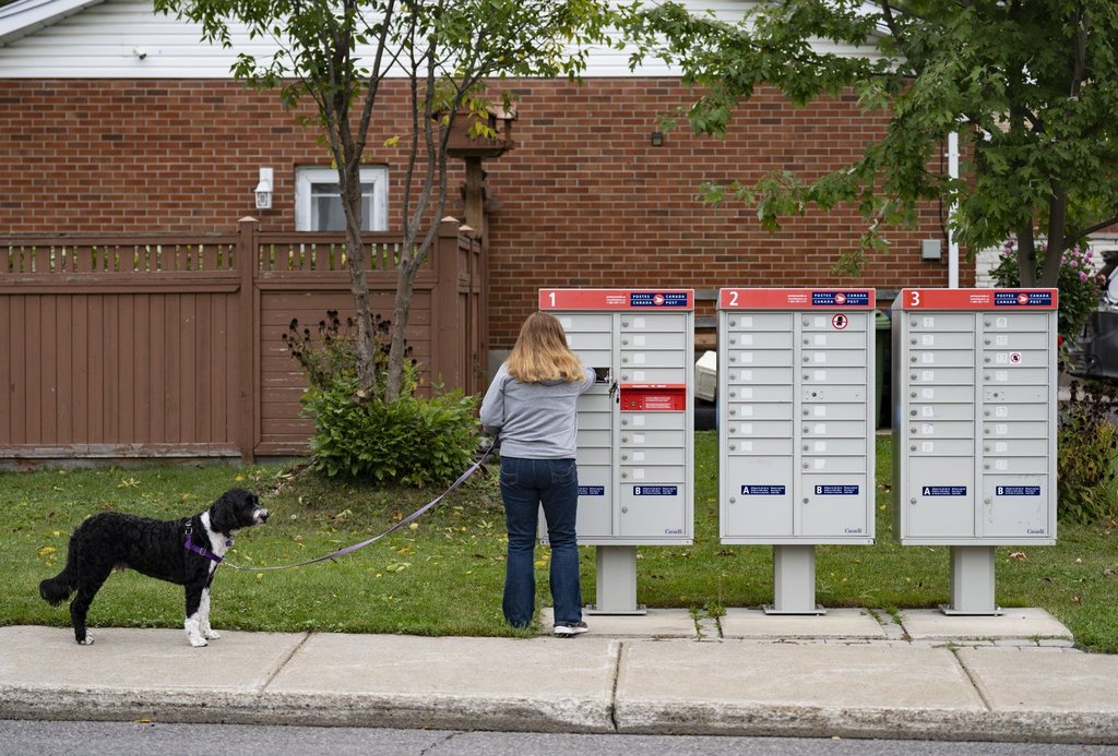 A woman checks for mail at her community mailbox in the Pointe-Claire neighbourhood of Montreal on Sept. 26, 2025. THE CANADIAN PRESS/Christinne Muschi.