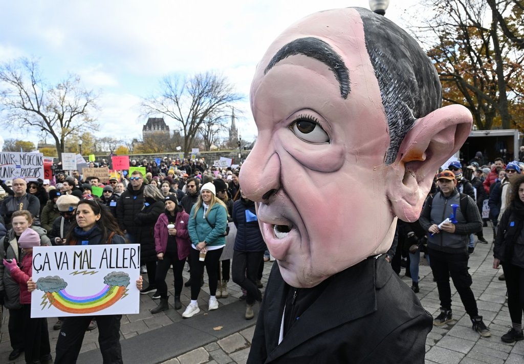 In front of the legislature in Quebec City, a giant puppet representing Quebec Health Minister Christian Dubé stands as people demonstrate against a law that changes how doctors are paid, Saturday, Nov. 1, 2025. THE CANADIAN PRESS/Jacques Boissinot