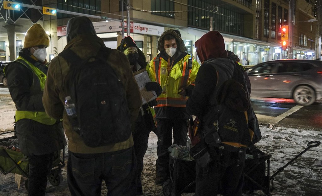 BeTheChangeYYC uutreach volunteer Chaz Smith, second right, offers help to the homeless on a -20 C night in Calgary on Tuesday, Dec. 14, 2021. 