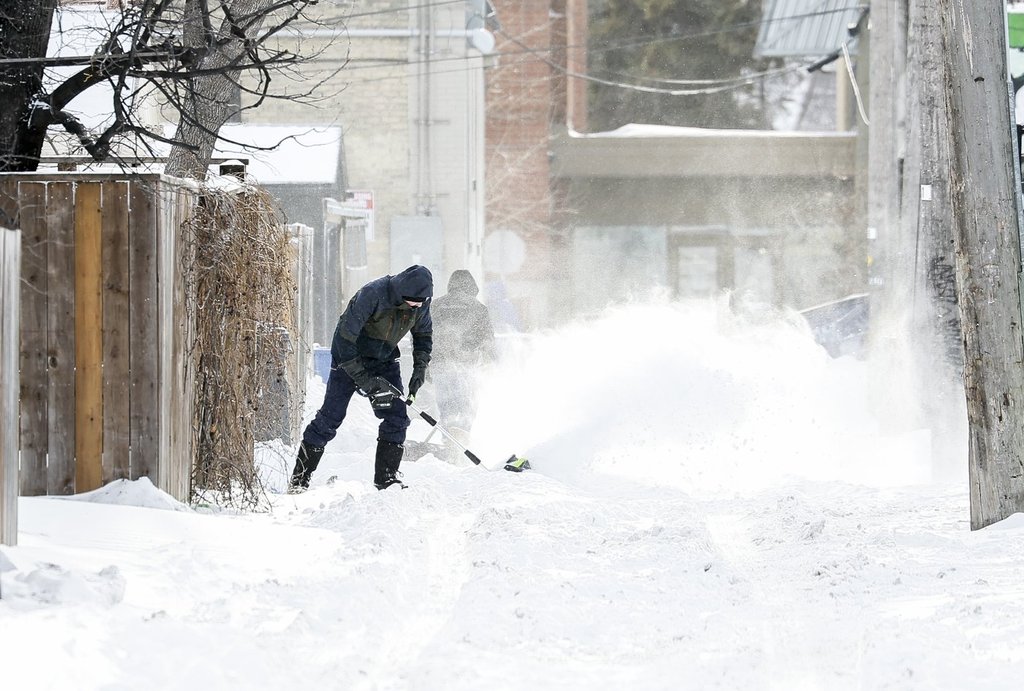 People clear snow after an overnight storm, in Winnipeg, Thursday, Dec. 18, 2025.