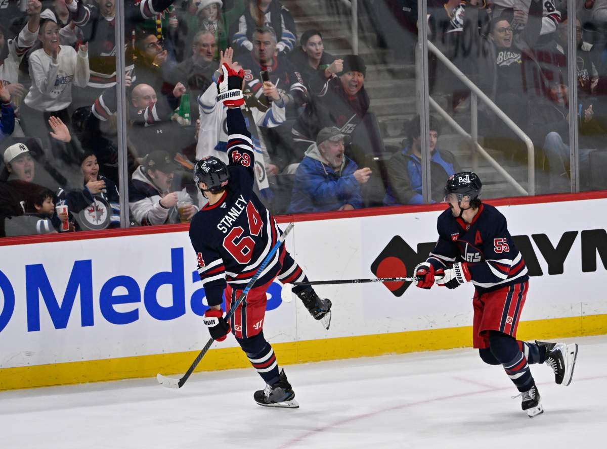 The Winnipeg Jets' Logan Stanley (64) celebrates his goal against the Ottawa Senators with Mark Scheifele (55) during the second period of their NHL hockey game in Winnipeg, Monday, Dec. 15, 2025.