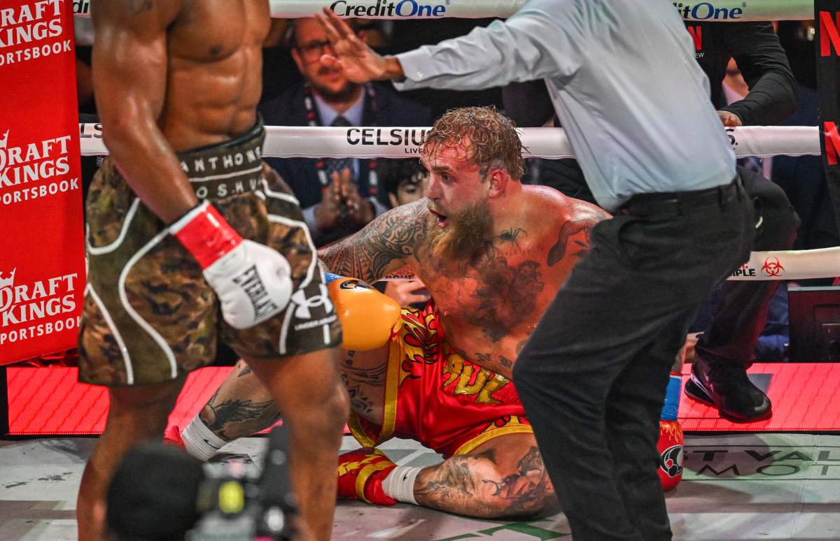 Referee Christopher Young counts over US boxer and influencer Jake Paul as he sits on the floor during his fight against British boxer Anthony Joshua (L) in a non-title heavyweight bout at the Kaseya Center in Miami, Florida, on December 19, 2025.