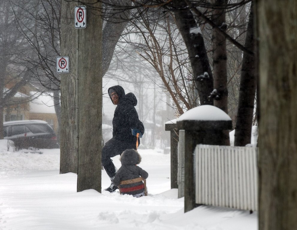 A resident takes advantage of a lull to take their child for a sleigh ride in St. John's on Friday, March 8, 2024. THE CANADIAN PRESS/Paul Daly.