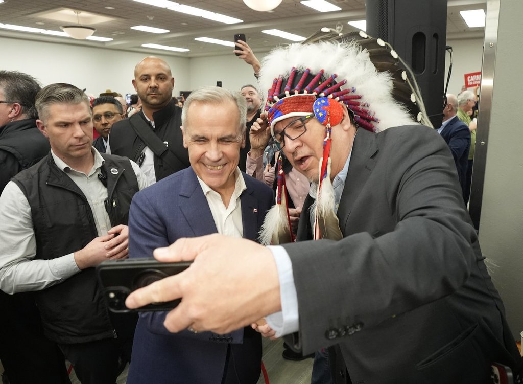 Pimicikamak Cree Nation Chief David Monias gets a selfie with Mark Carney at a federal election campaign rally in Winnipeg, Tuesday, April 1, 2025. THE CANADIAN PRESS/Adrian Wyld.