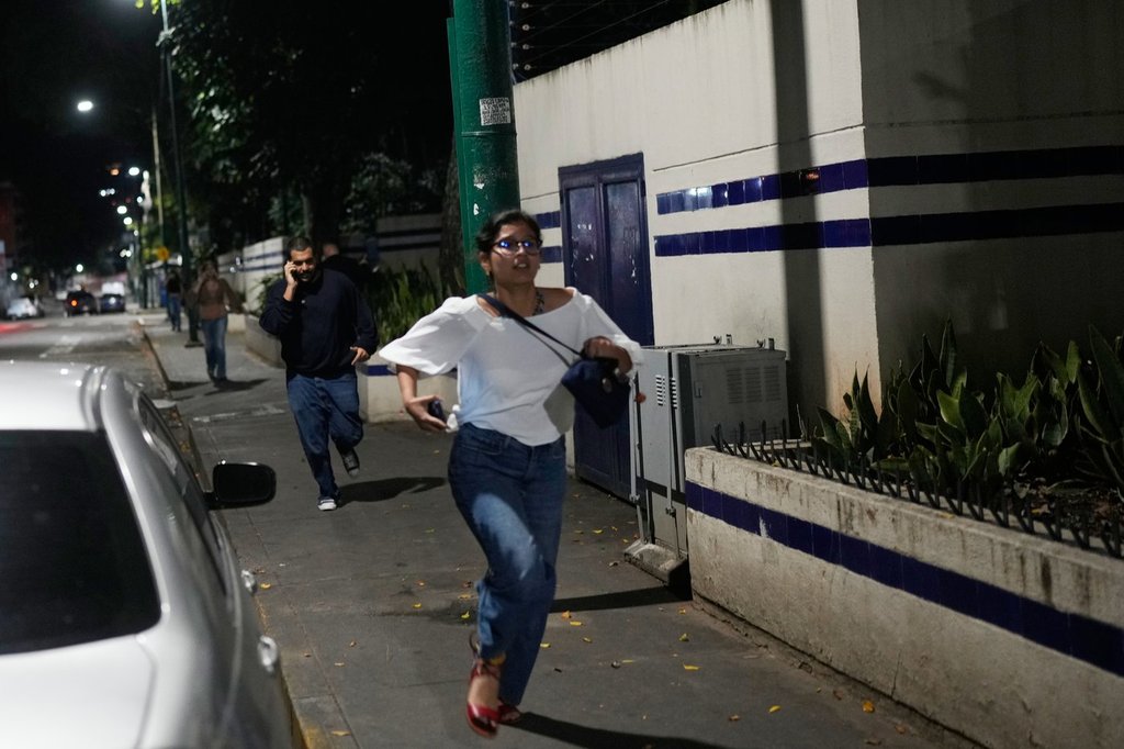 Pedestrians run after explosions and low-flying aircraft were heard in Caracas, Venezuela, Saturday, Jan. 3, 2026. (AP Photo/Matias Delacroix)