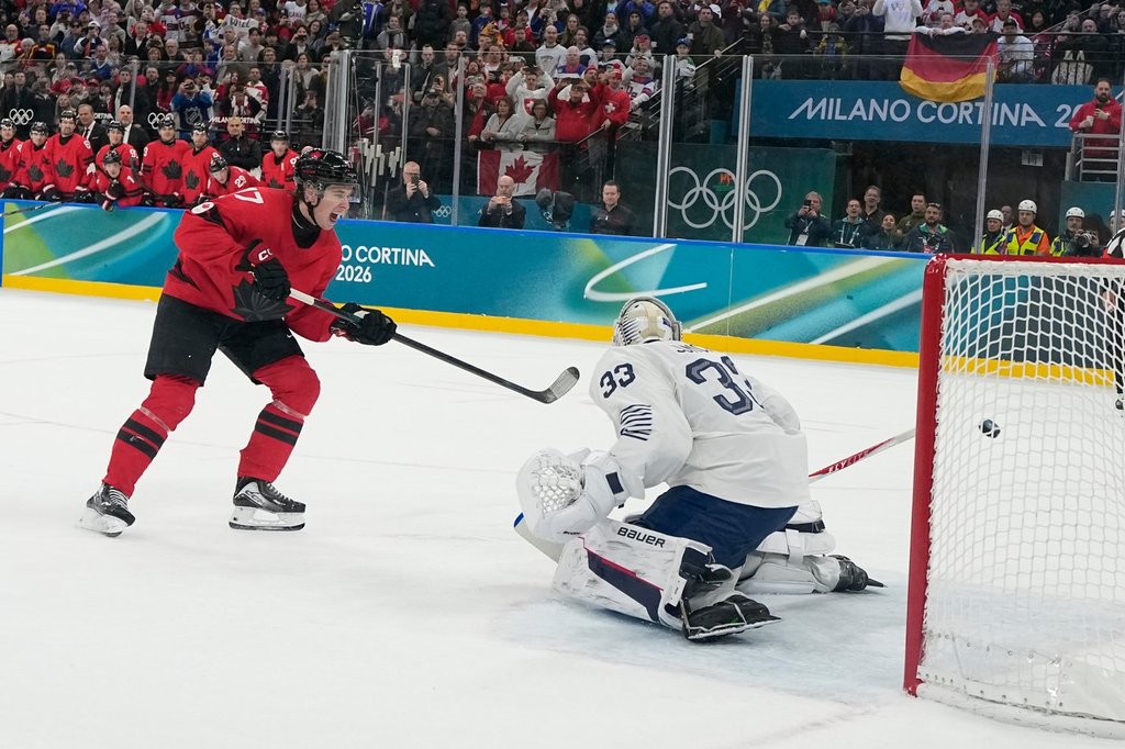 Canada's Macklin Celebrini (17) scores a goal on a penalty shot in the second period against France's goalkeeper Julian Junca (33) during a preliminary round game of men's ice hockey between Canada and France at the 2026 Winter Olympics, in Milan, Italy, Sunday, Feb. 15, 2026. (AP Photo/Hassan Ammar).