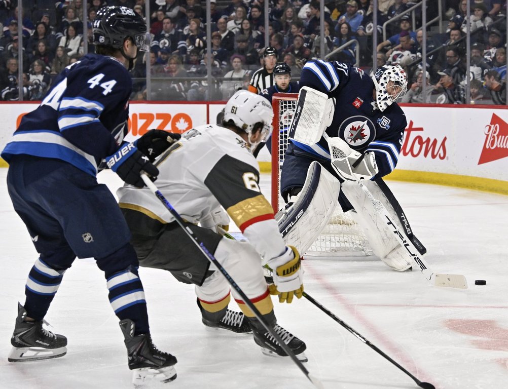 Winnipeg Jets goaltender Connor Hellebuyck (37) clears the puck from behind the net after it was dumped in by he Vegas Golden Knights during the first period of their NHL hockey game in Winnipeg, Tuesday March 24, 2026.