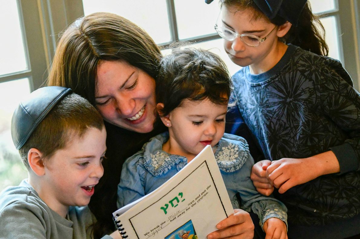 Chaya Raskin of Brattleboro, Vt., is surrounded by her children as she reads the Haggadah, a special book containing the story of the Exodus, prayers, and rituals, on Tuesday, March 31, 2026, ahead of Passover on Wednesday.(Kristopher Radder/The Brattleboro Reformer via AP).
