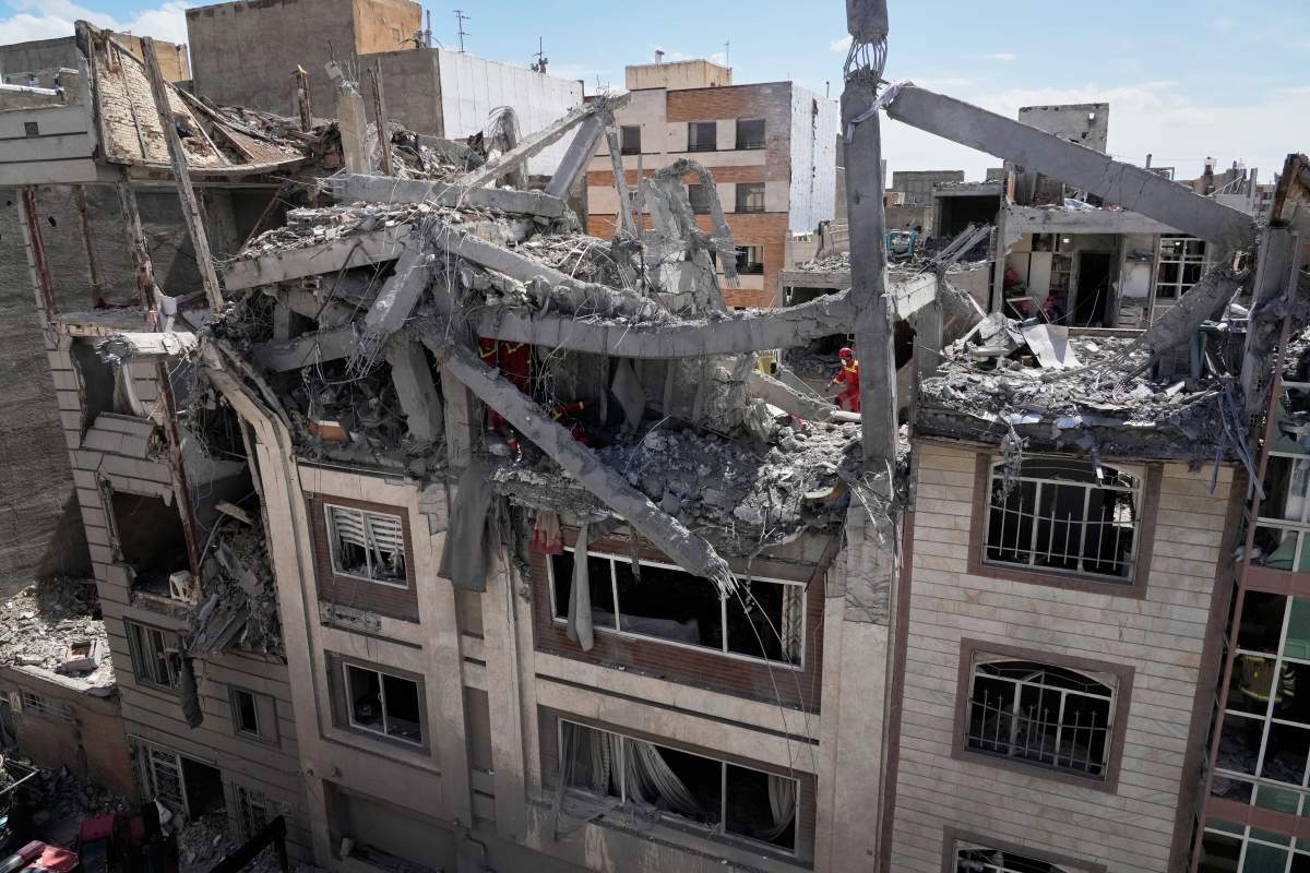 First responders inspect a residential building hit in an earlier U.S.-Israeli strike in Tehran, Friday, March 27, 2026.