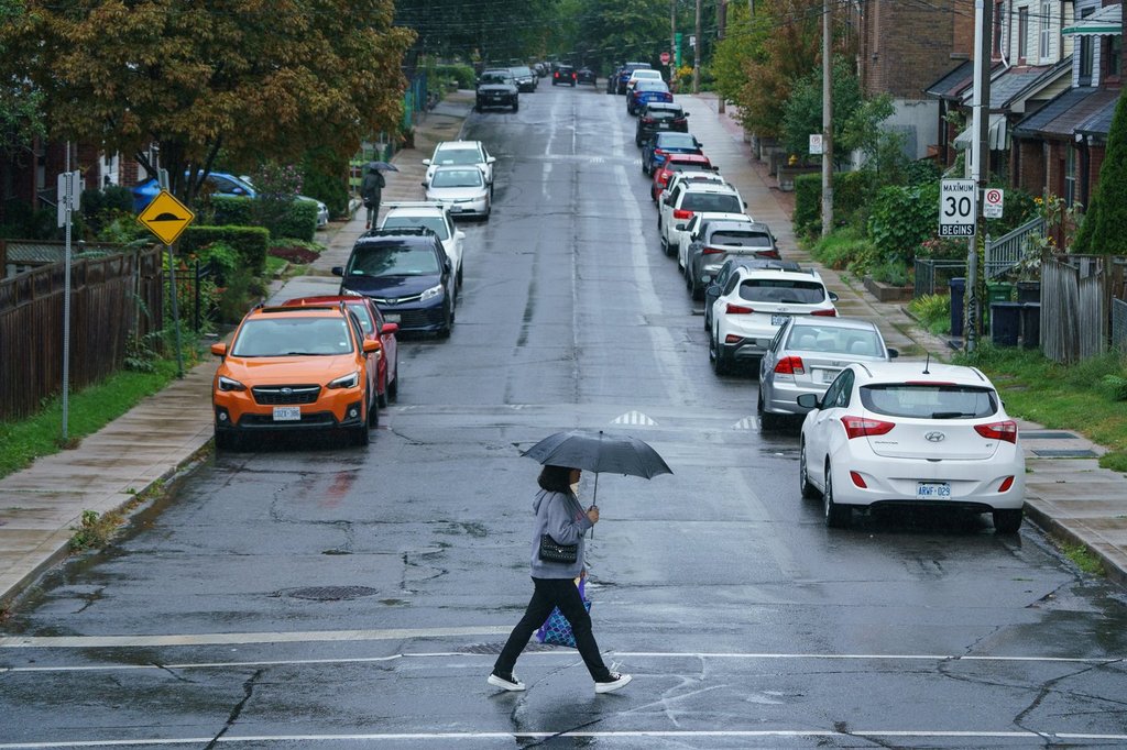 A person carries an umbrella during a downpour of rain in Toronto on Tuesday, Sept. 27, 2022. 