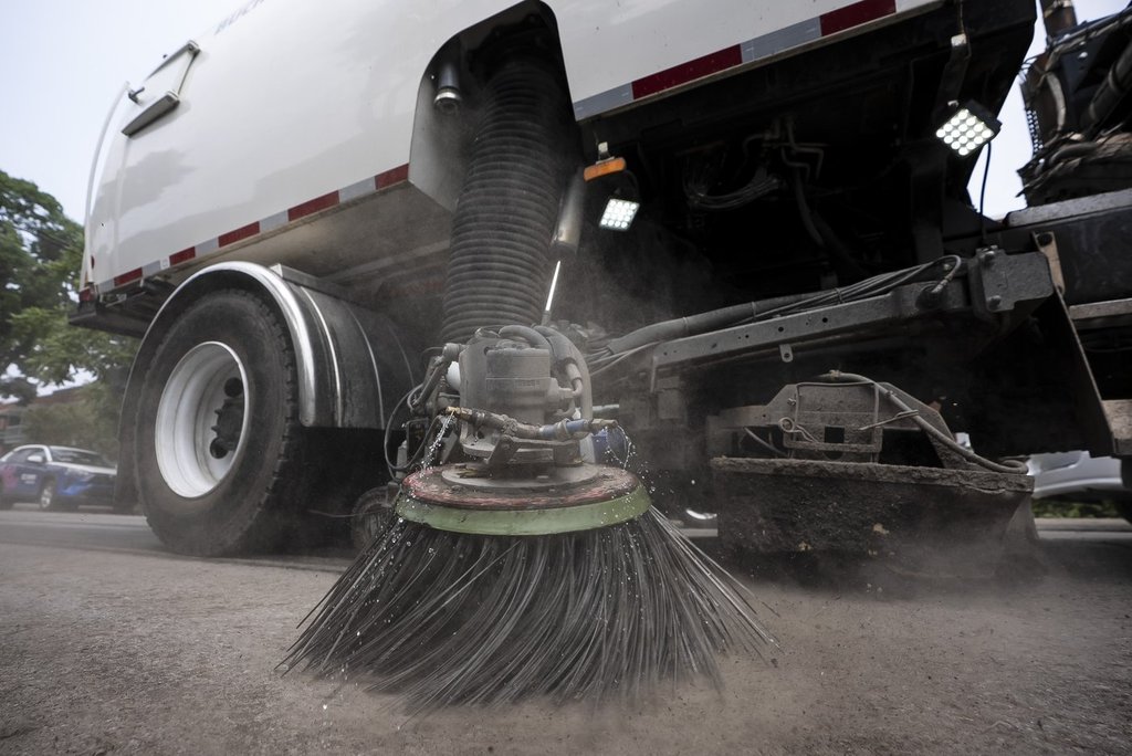 Street cleaning vehicles sweep the street following flash flooding after heavy rains in Montreal on Monday July 14, 2025. 