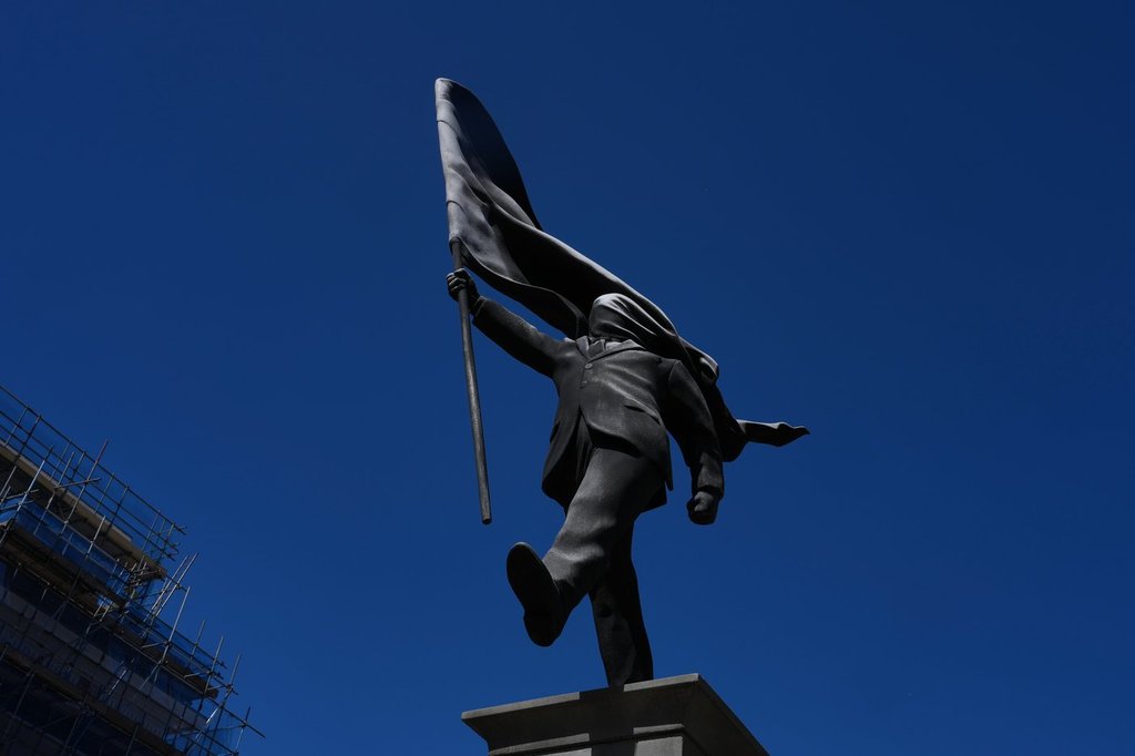 A statue of a man holding a flag covering his face, and signed 'Banksy', which has appeared in Waterloo Place in London, Thursday, April 30, 2026