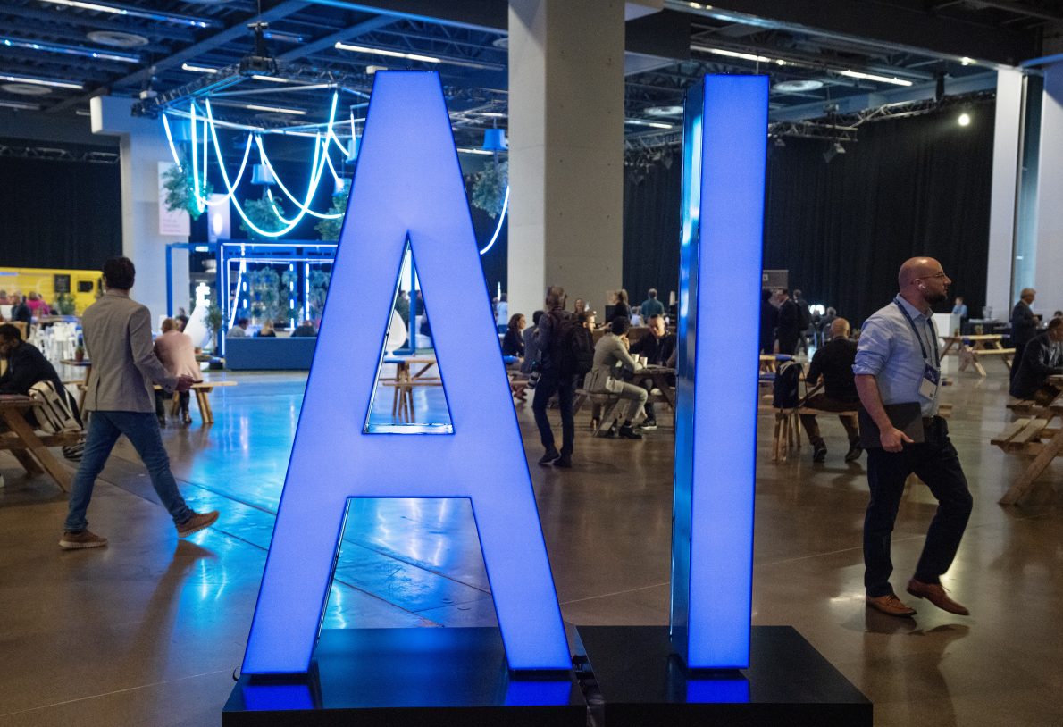People walk past an AI sign at the All In artificial intelligence conference on Sept. 28, 2023, in Montreal.THE CANADIAN PRESS/Ryan Remiorz.