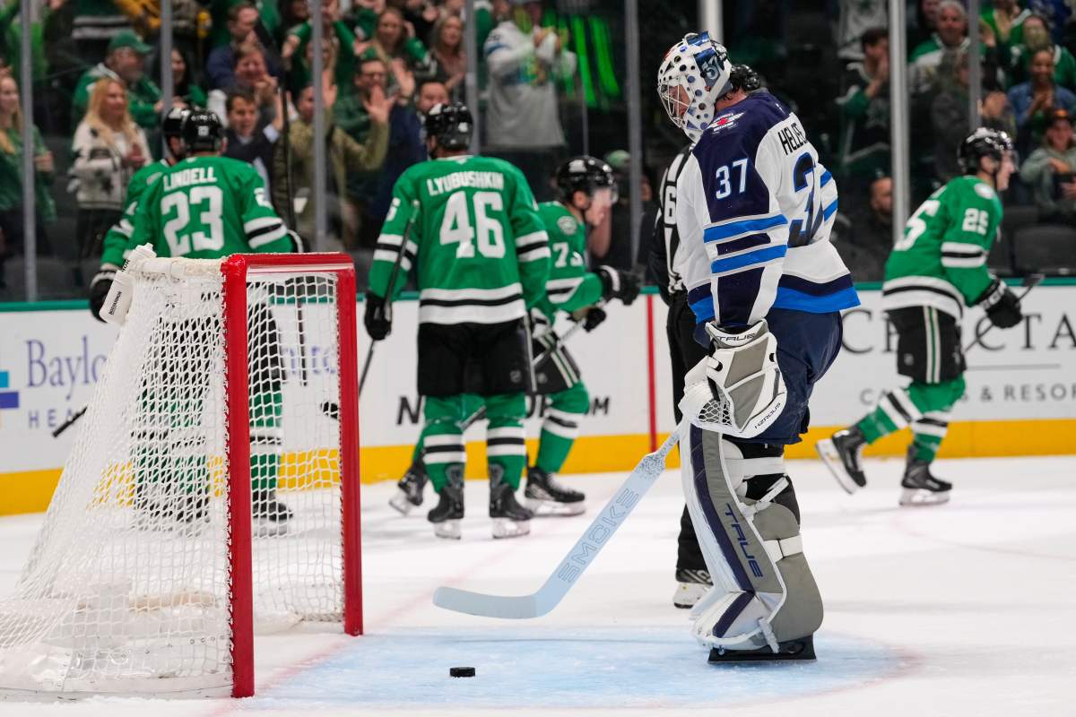 Winnipeg Jets goaltender Connor Hellebuyck (37) looks down at the ice as the Dallas Stars celebratge a goal by Arttu Hyry in the first period of an NHL hockey game Thursday, April 2, 2026, in Dallas. (AP Photo/Tony Gutierrez).