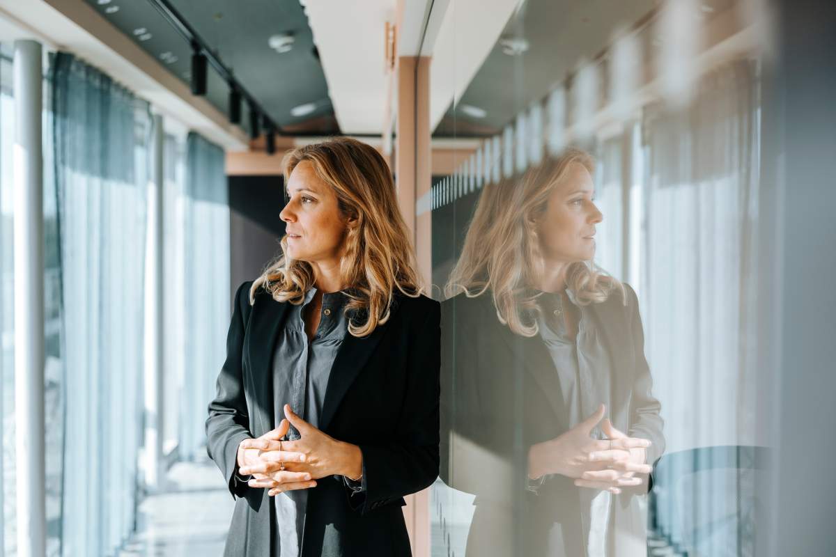 A nervous businesswoman looks out a window.