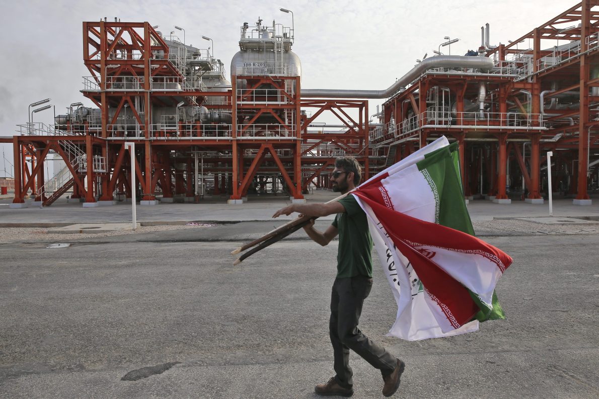 FILE - In this Saturday, March 16, 2019 photo, an Iranian worker carries Iranian flags prior to an inauguration ceremony of a natural gas refinery at the South Pars gas field on the northern coast of the Persian Gulf, in Asaluyeh, Iran.