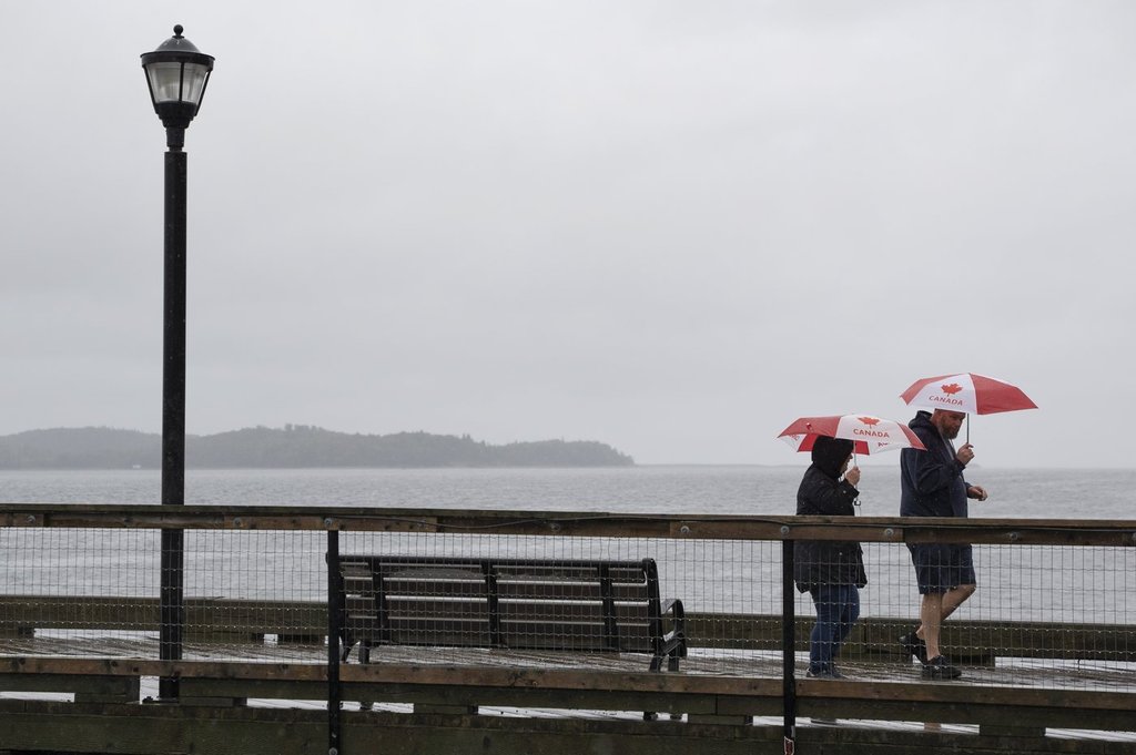 Pedestrians shield themselves with umbrellas while walking along the Halifax waterfront as rain falls ahead of Hurricane Fiona making landfall in Halifax, Friday, Sept. 23, 2022. THE CANADIAN PRESS/Darren Calabrese.