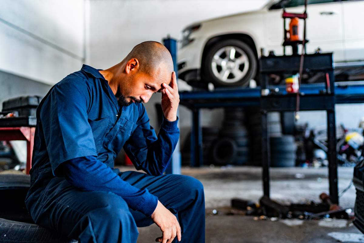 A fired automotive mechanic rubs his forehead before clearing his workspace. FG Trade Latin/Getty Images