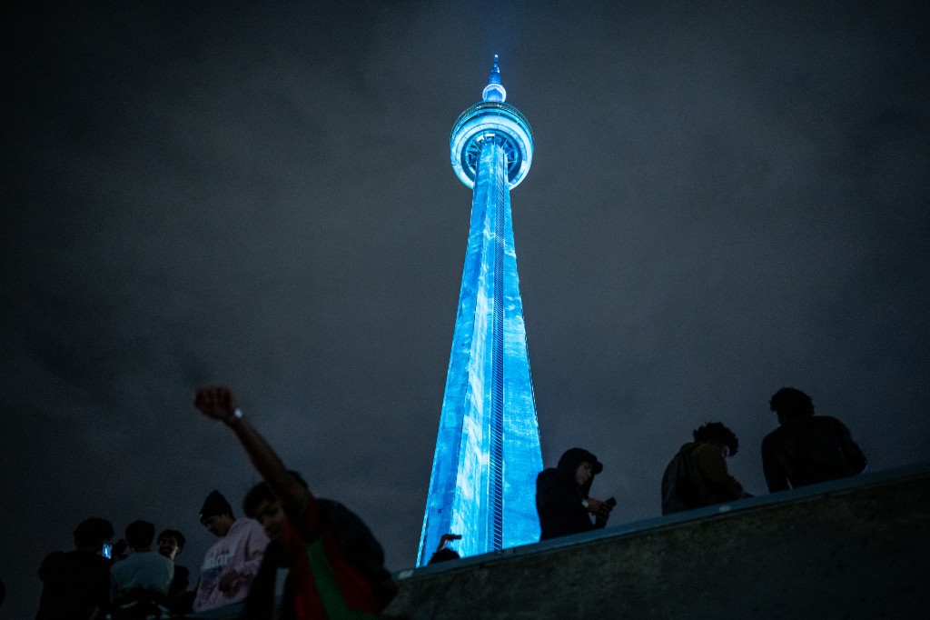 Fans of Drake climb a concrete structure as they gather near the CN Tower for a video projection promoting the upcoming album 'ICEMAN' in Toronto on Friday, May 14, 2026.