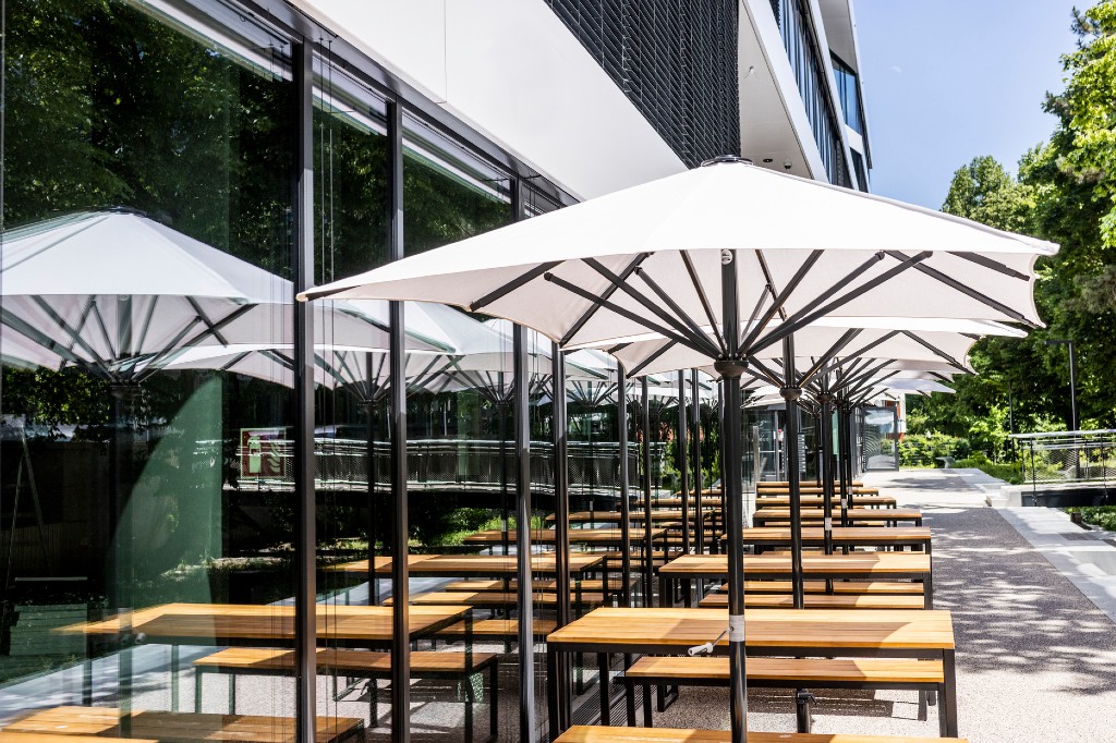 A file photo of empty outdoor tables under white umbrellas at a restaurant.