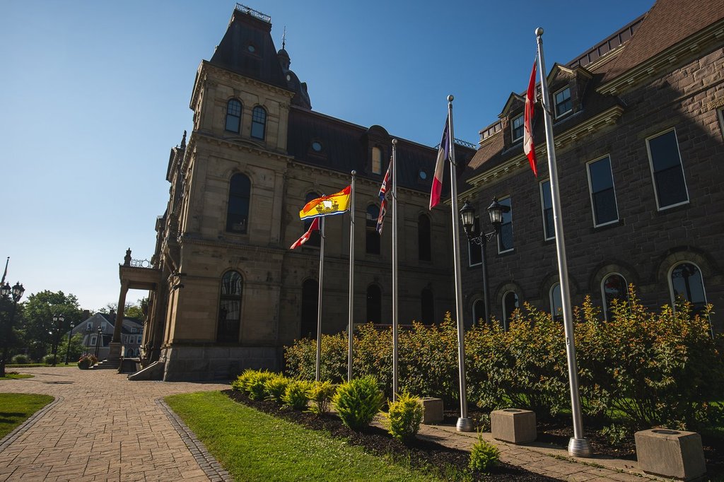 The New Brunswick flag flies in a row of flags beside the Legislative Assembly Building, home of the provincial legislature, in Fredericton, Saturday, July 26, 2025. THE CANADIAN PRESS/Giordano Ciampini.