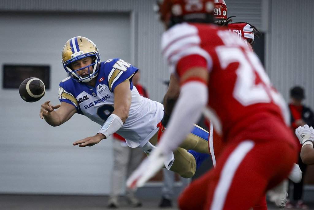 Winnipeg Blue Bombers quarterback Zach Collaros, left, makes a diving pass against the Stampeders during first half CFL football action in Calgary on June 5, 2026.THE CANADIAN PRESS/Jeff McIntosh.